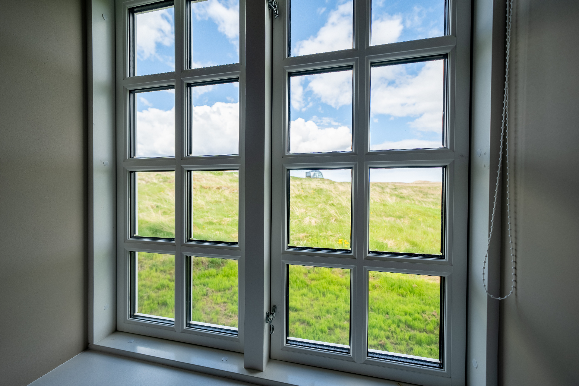 Standard twin room bed facing a paned window with countryside view
